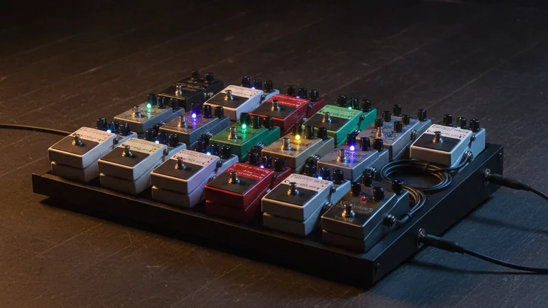Guitar effects pedal board with colorful indicator lights on dark stage