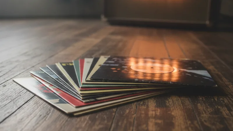 Stack of indie rock vinyl records on worn wooden floor with amp glow