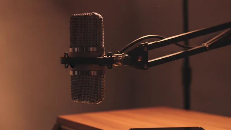 Close-up of a vintage condenser microphone on a boom arm and a Rhodes electric piano keyboard partially visible in a softly lit home studio with an iPhone resting on the piano, soft warm low key lamp lighting, candid still-life photography in editorial style, intimate soulful mood, warm amber and burgundy tones