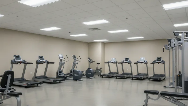 A sterile brightly lit gym interior with flat ceiling speakers and beige walls